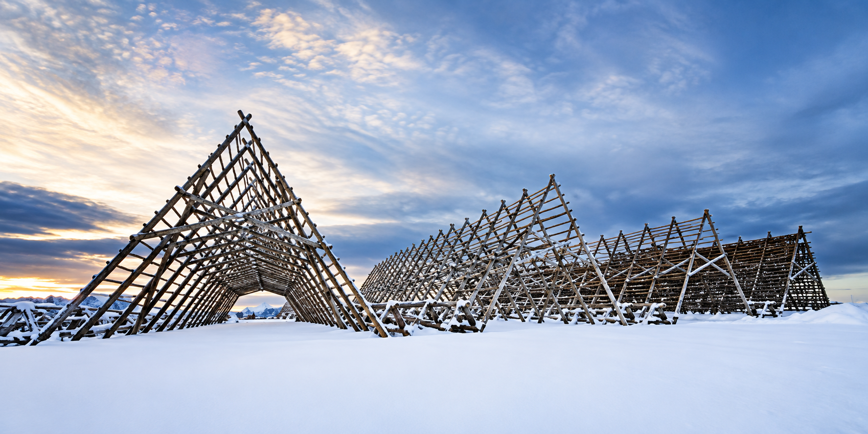 Snow-covered traditional fish drying racks at Hjellan on Nautøya beneath an open Arctic sky